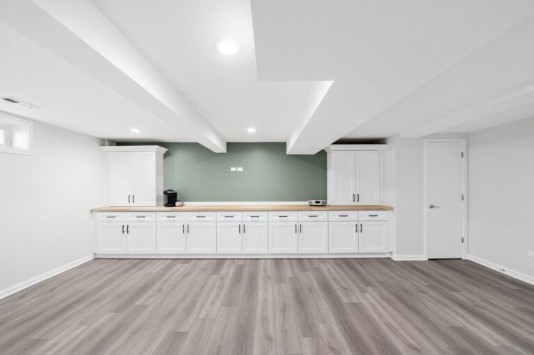 A basement with wooden floor equipped with cabinets and countertop