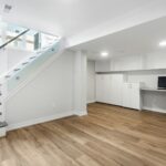 A basement with a desk, computer, and stairs