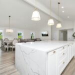 A remodeled large white kitchen with a marble island