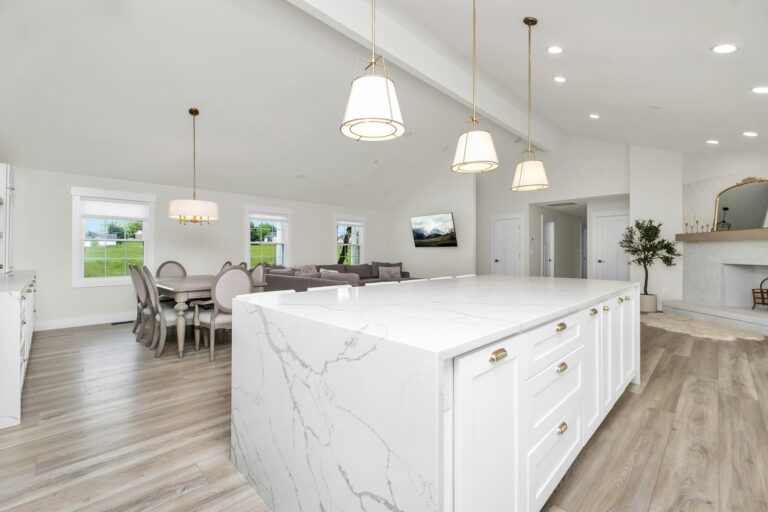 A remodeled large white kitchen with a marble island