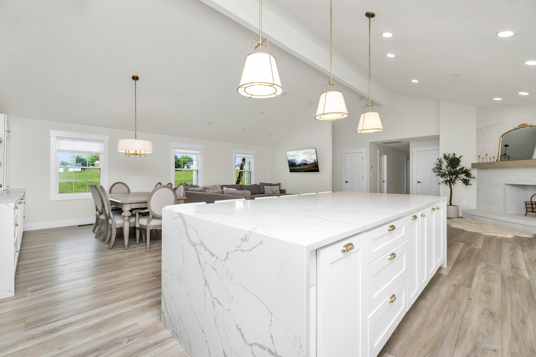 A remodeled large white kitchen with a marble island