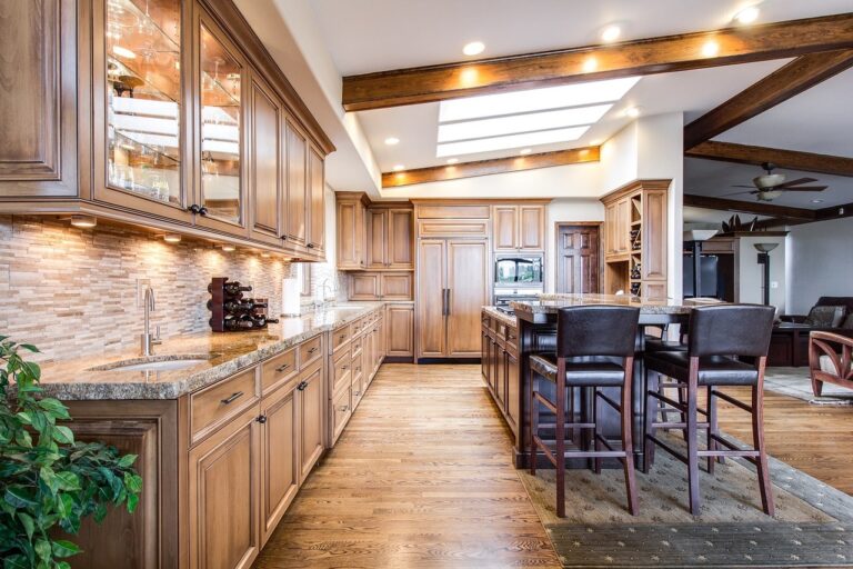 A kitchen with brown cabinets, kitchen island and wooden chairs