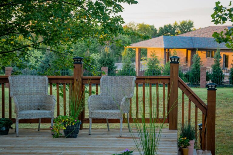 A porch with two chairs looking over a grass field