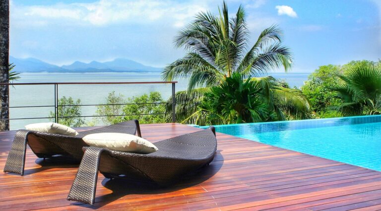 Wood decking with two chairs next to a pool overlooking the sea